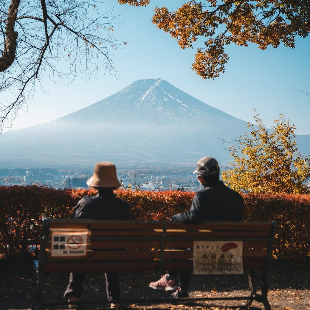 couple sitting on a bench and looking at mount fuji