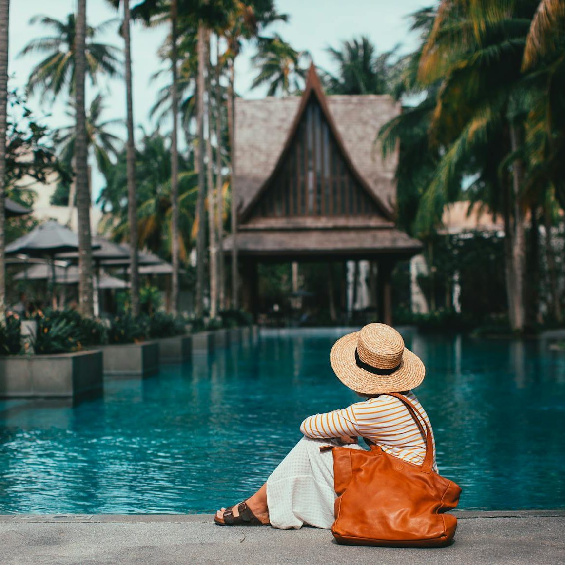 unrecognizable woman sitting on poolside in peaceful resort