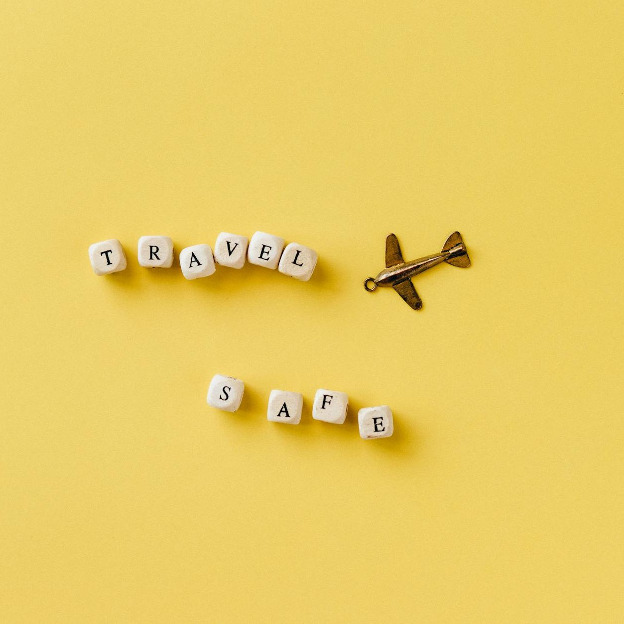 beads with letters arranged in a text saying travel safe and a small pendant in a shape of an airplane